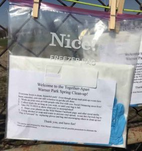 A plastic bag hanging on a fence with earth day cleanup directions inside