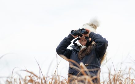 Girl looking through binoculars dressed in winter clothing