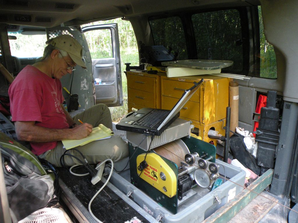 Ken Bradbury works on his laptop inside a truck doing field work
