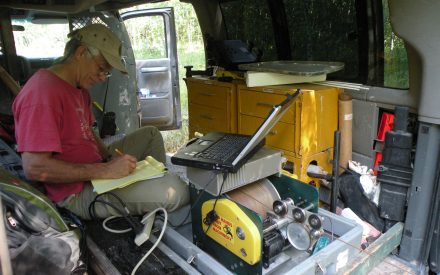 Ken Bradbury works on his laptop inside a truck during field work