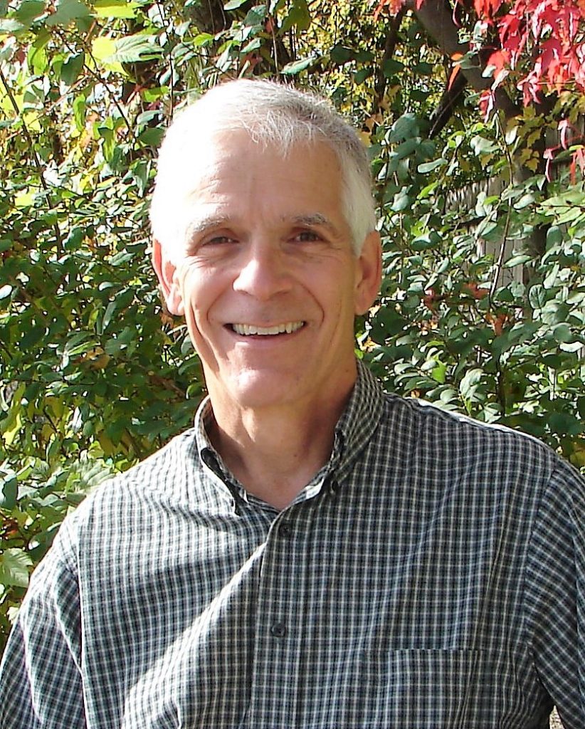 Ken Bradbury stands in front of fall foliage