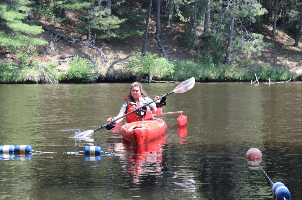 Woman in adaptive kayak paddling on a lake.