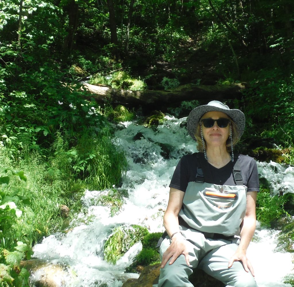Woman sitting next to running stream in the woods