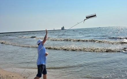 Boy throws rake into water along beach