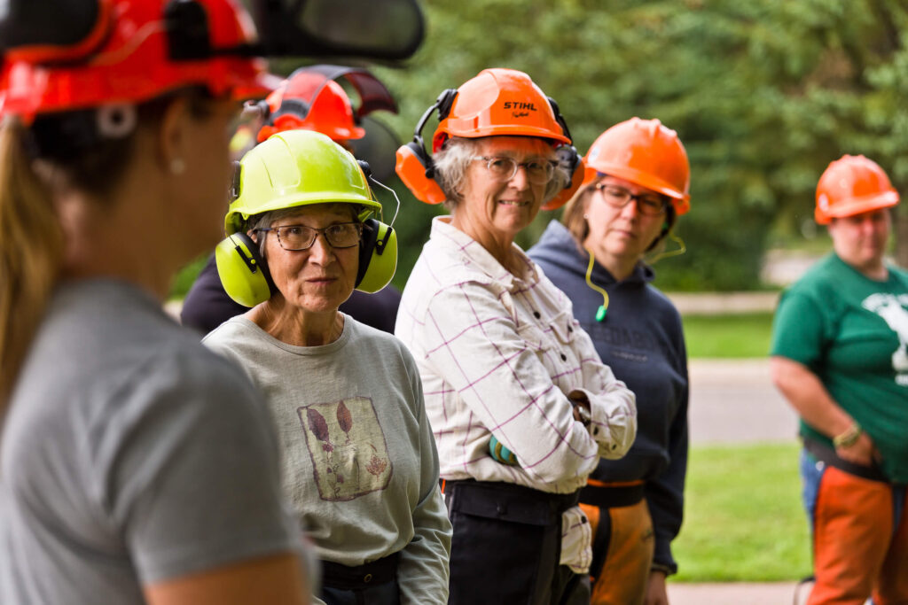A group of women wearing chainsaw safety equipment