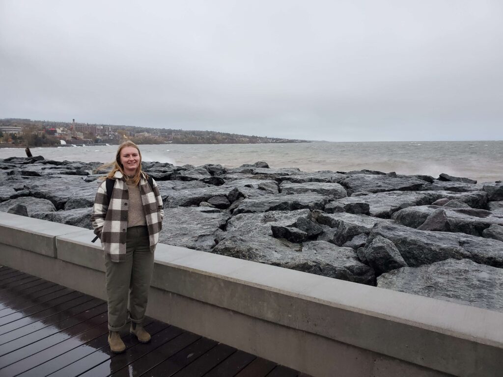 Woman standing next to rocky lakeside