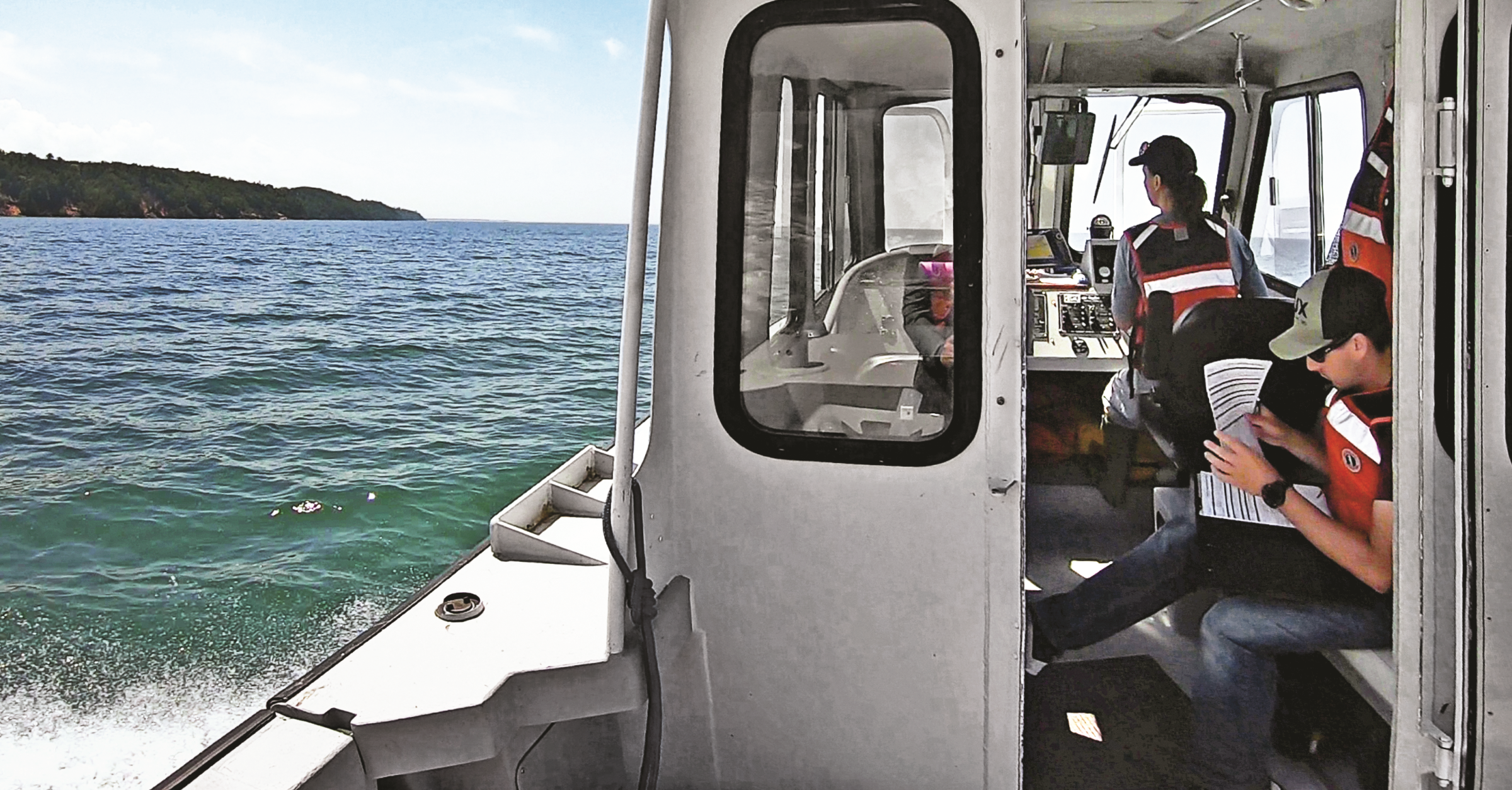 Three students riding in a research boat on Lake Superior.