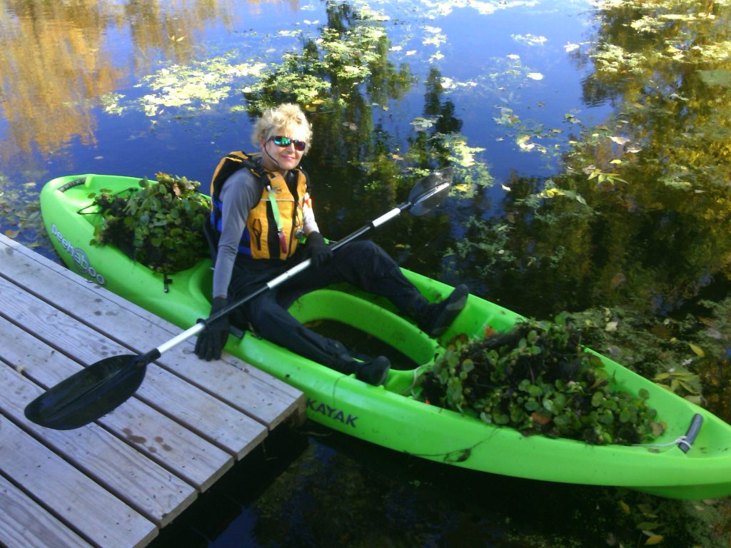 Valerie in a kayak with water hyacinth she pulled in her kayak all around her.