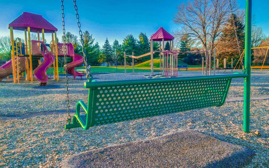 A bench swing and other brightly colored playground equipment