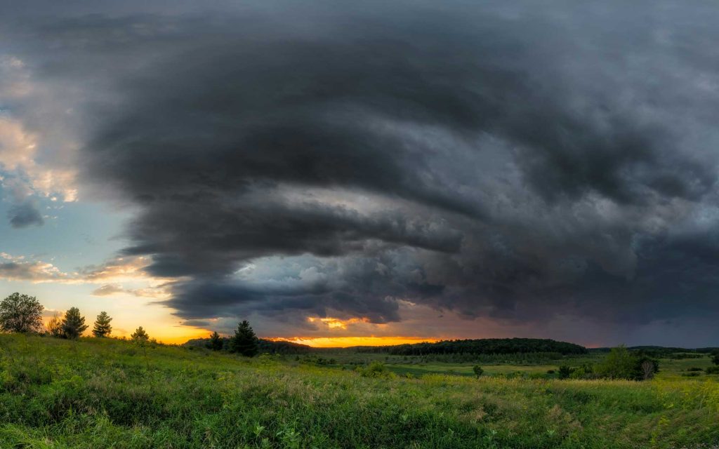A very dark storm cloud in front of a bright orange sunset