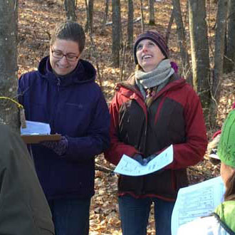 Two women in a group of women identifying tree species in the fall