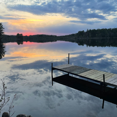 The sunset reflecting on a calm lake with a pier in the foreground