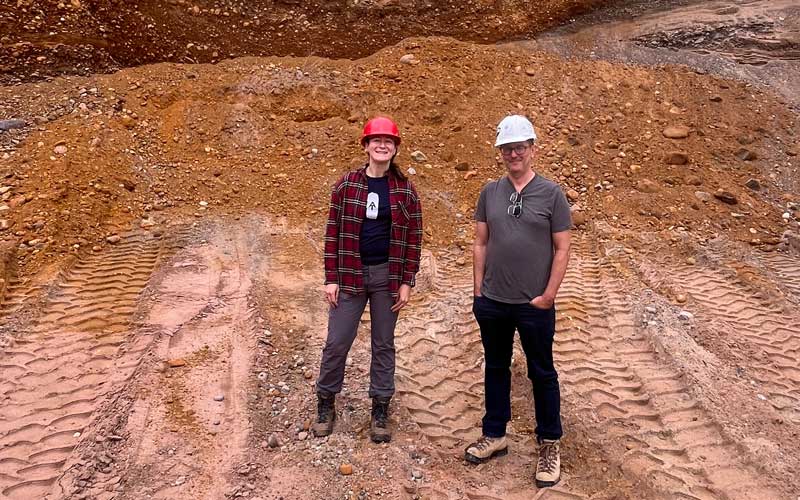 A woman and a man standing in front of a large area of soil recently excavated