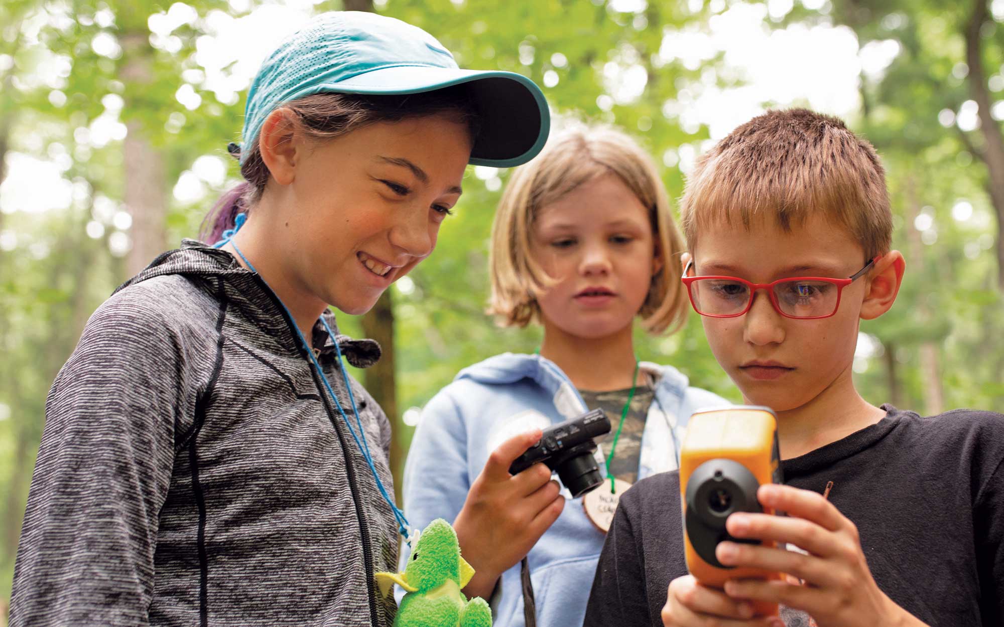 Three children in a woods using a hand held laser thermometer