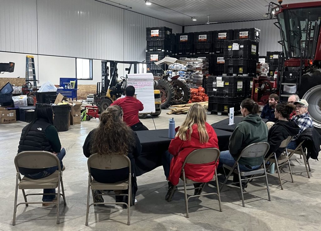 A group of farmers sitting around a table listening to a presentation