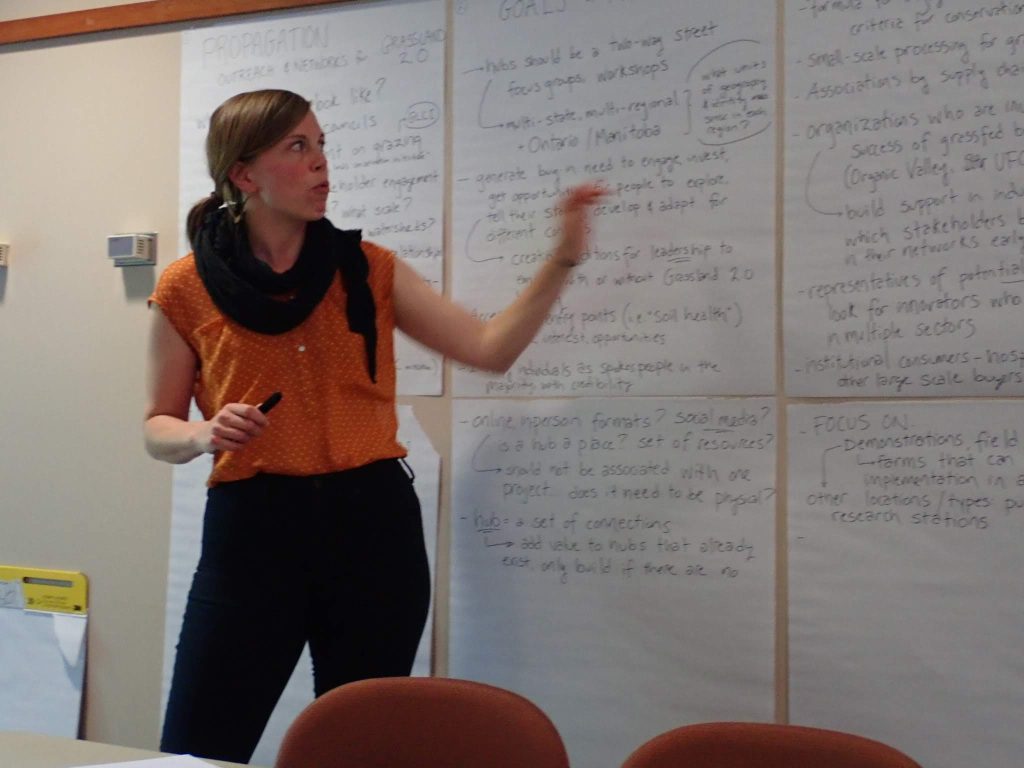 Greta Landis standing up and talking in front of a group going over results on a flip chart