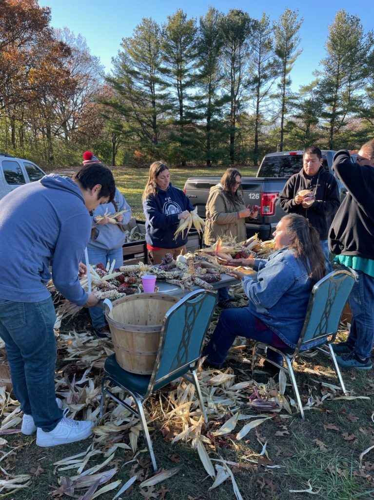 People sitting around a table braiding corn