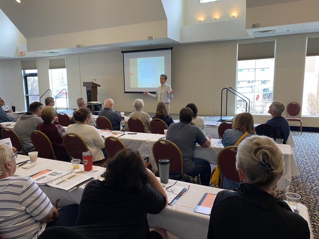 A man giving a presentation to a room full of individuals