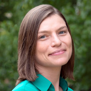 Headshot of Shailah Handy. A woman with shoulder length brown hair wearing a green shirt