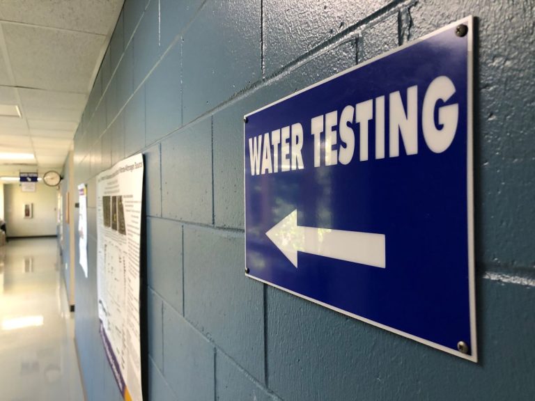 A sign that says water testing with an arrow in a hallway