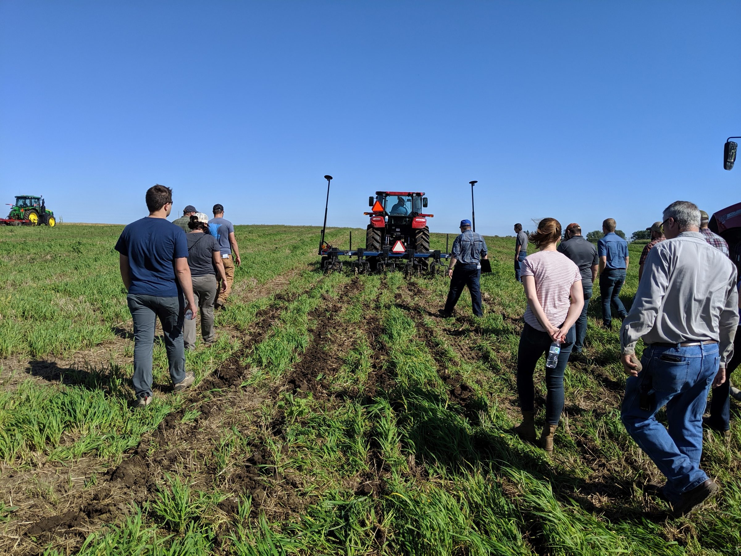 Large group of people on a farm walking behind tillage equipment. This photo was taken at the Arlington Ag Research Station for an Ag 101 training hosted for ag educators by Kevin Erb. This is a strip tillage.
