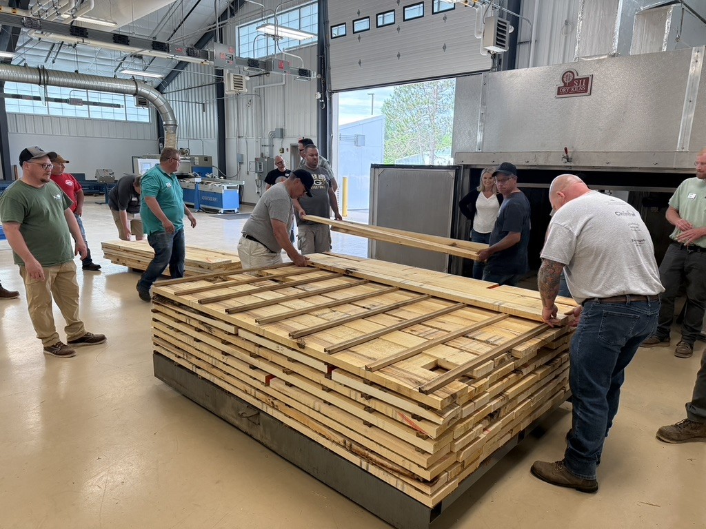 Teachers from the Wood Industry Teacher Camp learn about stacking lumber before pushing the charge into the dry kiln.